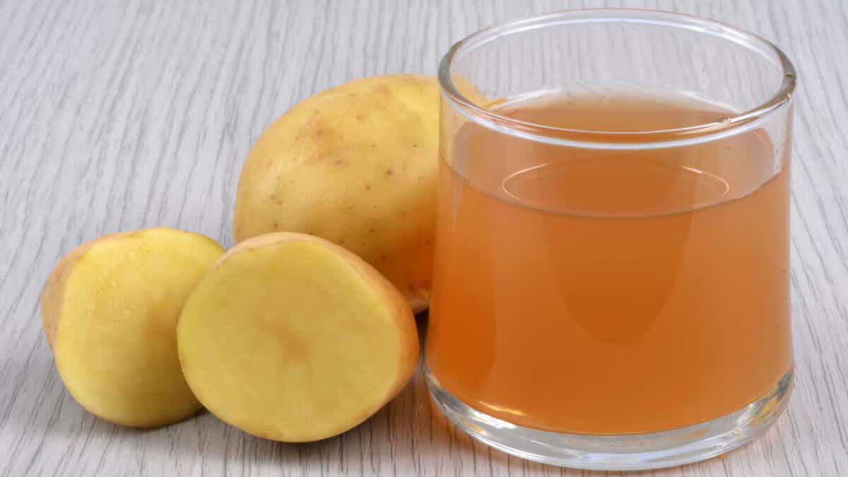 Vaso con zumo de patatas, junto a este tubérculo.