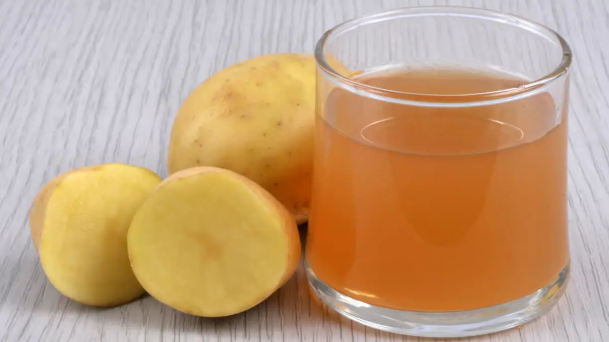 Vaso con zumo de patatas, junto a este tubérculo.