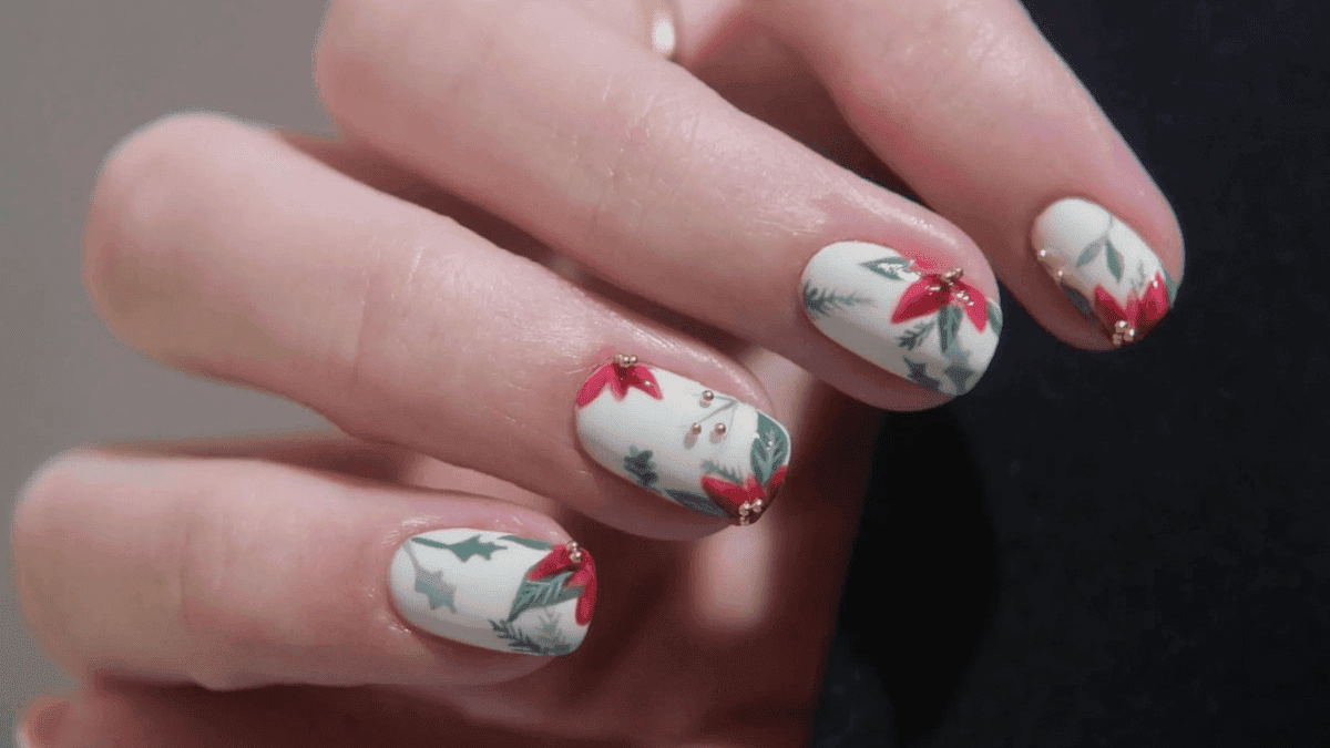 Uñas cortas pintadas con flores de Navidad, muérdago y pino.