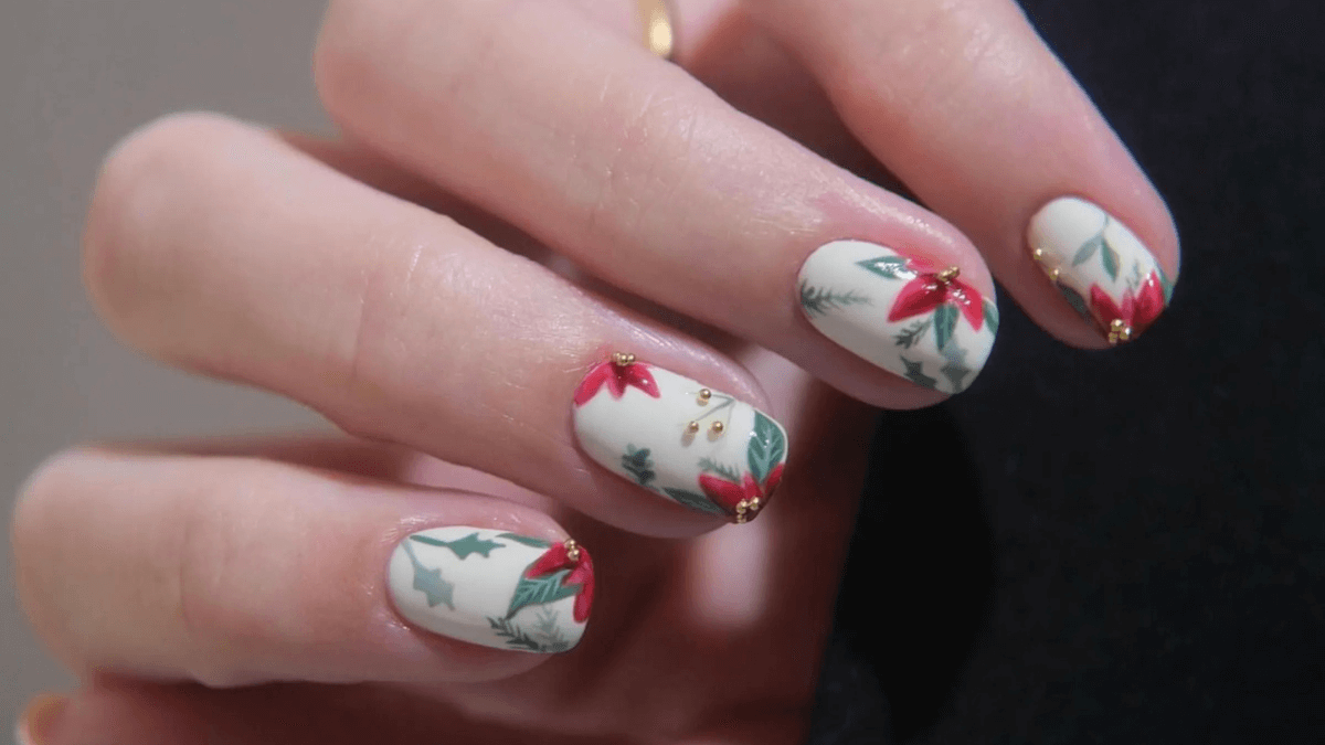 Unhas curtas pintadas com flores de Natal, visco e pinheiro.