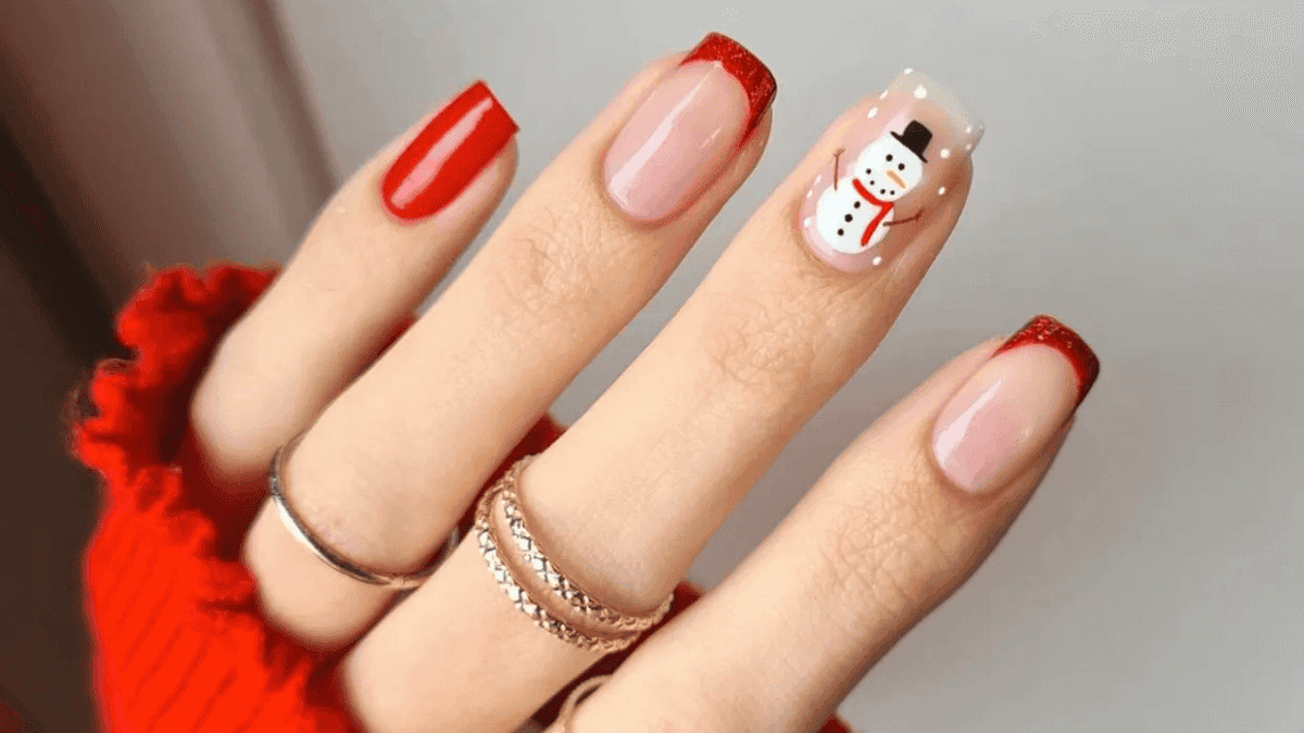 Uñas cuadradas con manicura francesa roja y un muñeco de nieve en un dedo.