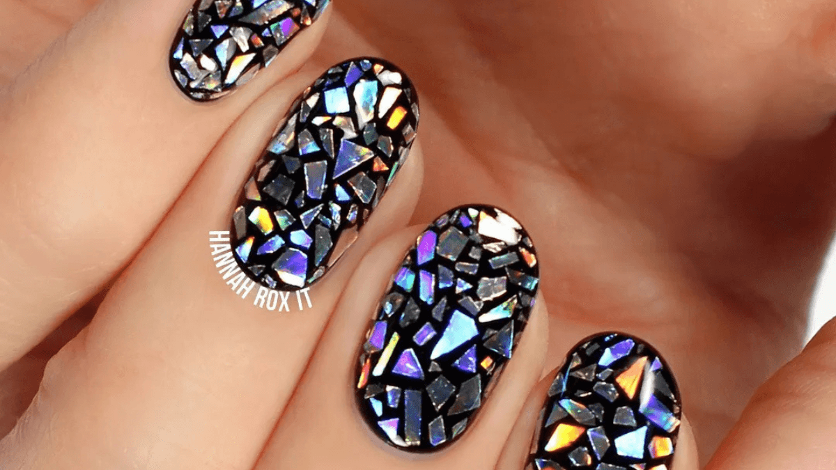 Base de uñas negras con detalles de cristales encima.