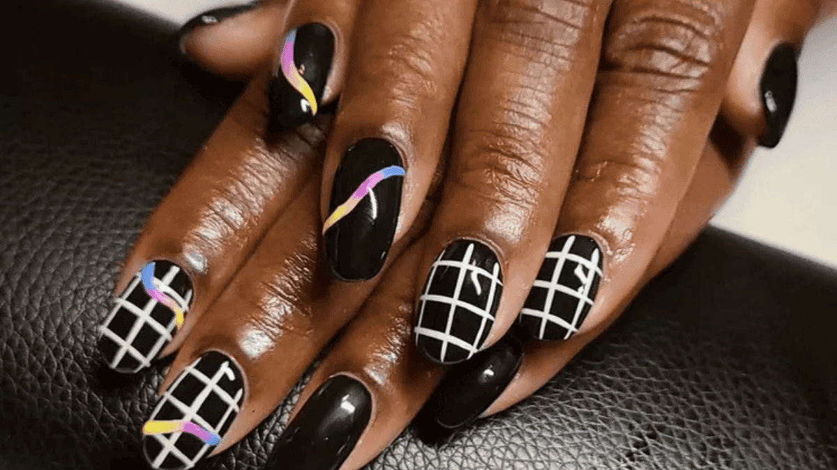 Uñas negras con líneas cuadradas blancas y otras de colores más fluidas.