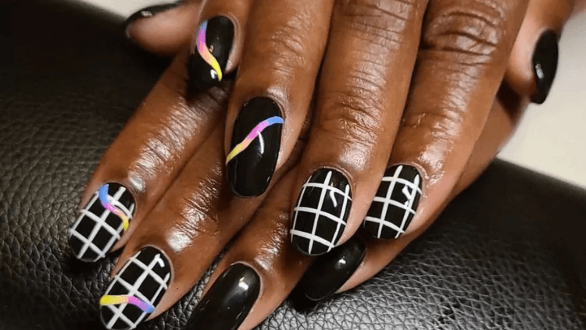 Uñas negras con líneas cuadradas blancas y otras de colores más fluidas.