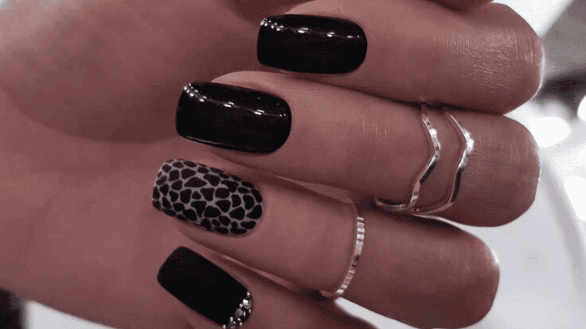 Uñas negras con el diseño de leopardo en el dedo anular.