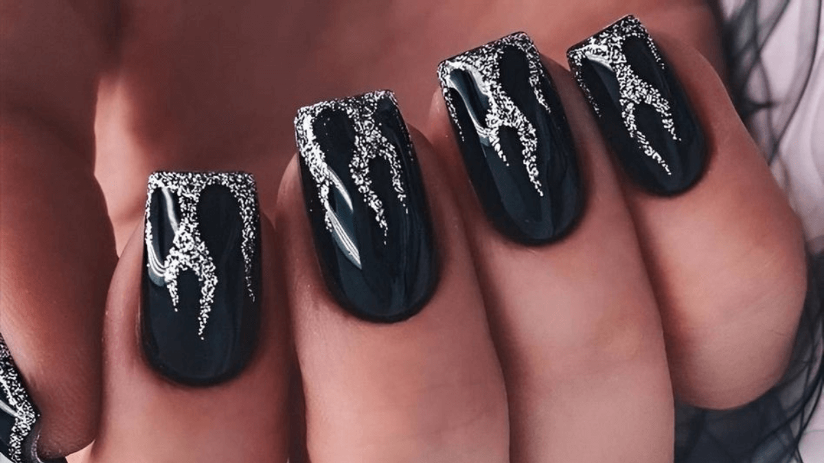 Uñas negras con llamas en plateado en las puntas.