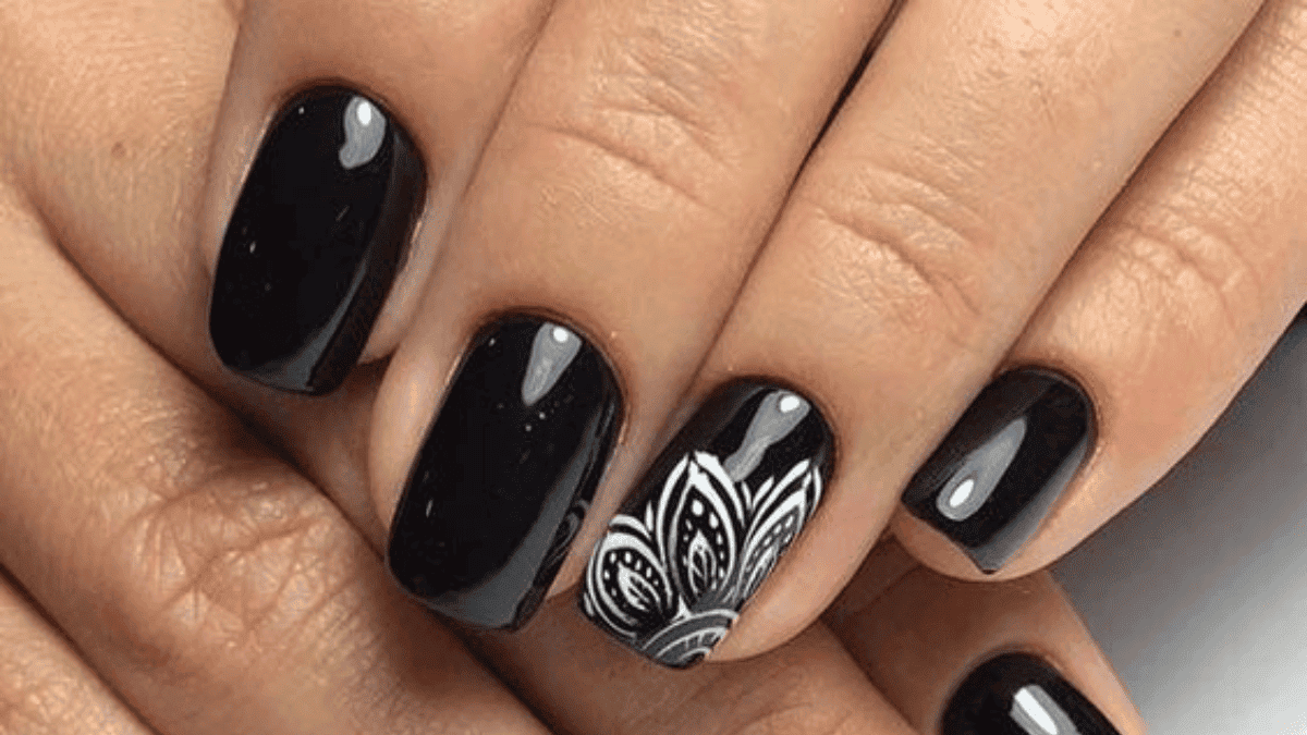 Uñas negras con mandala en el dedo anular.