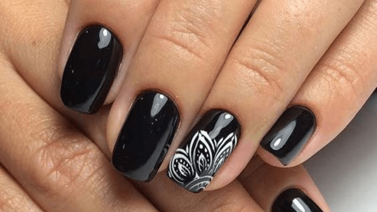 Uñas negras con mandala en el dedo anular.