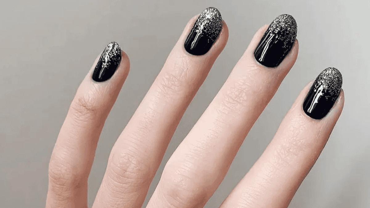 Uñas negras con plateado en las puntas.
