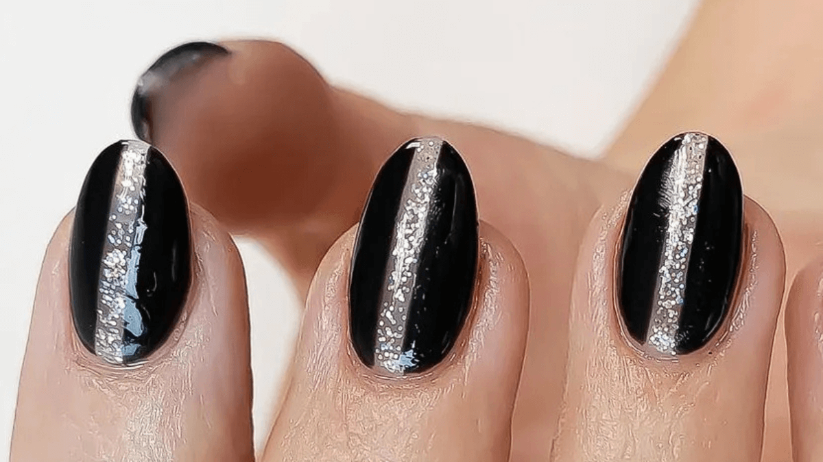Uñas con base negra con glitter en el centro.