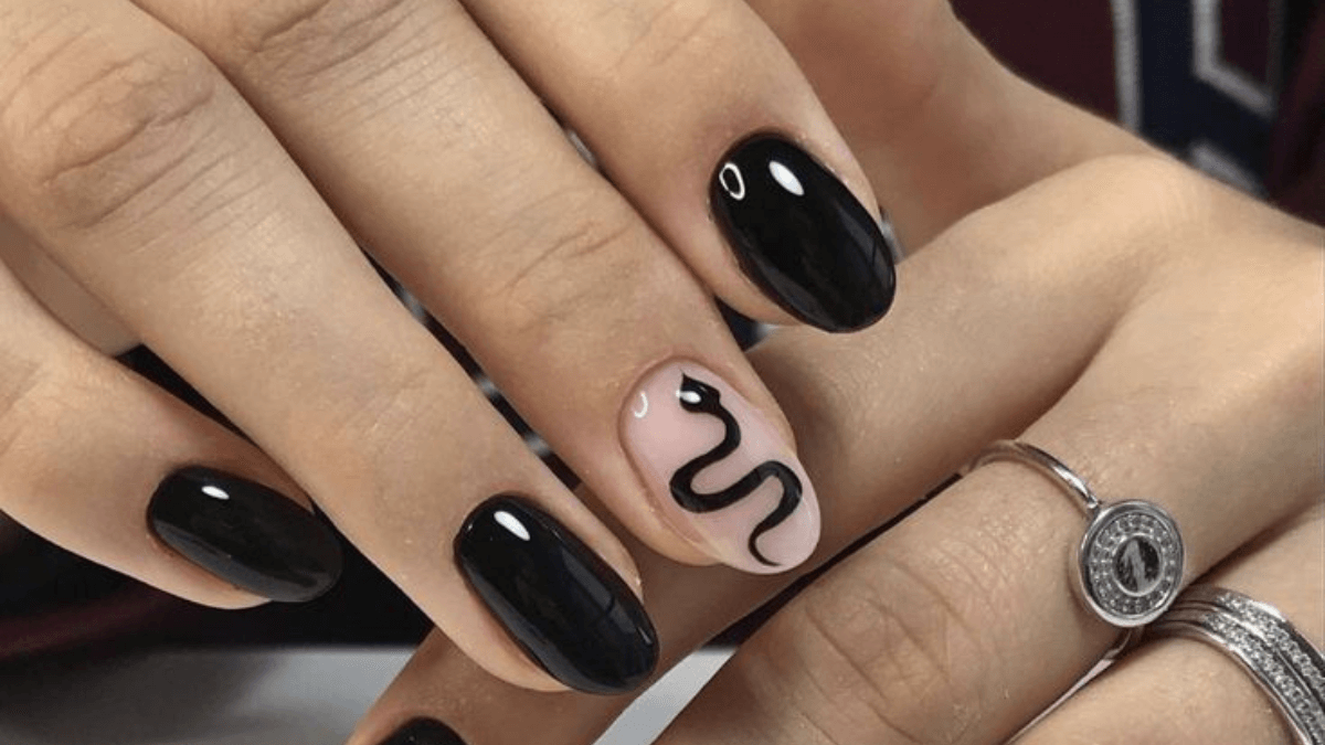 Uñas negras un dedo índice con el diseño de una serpiente.