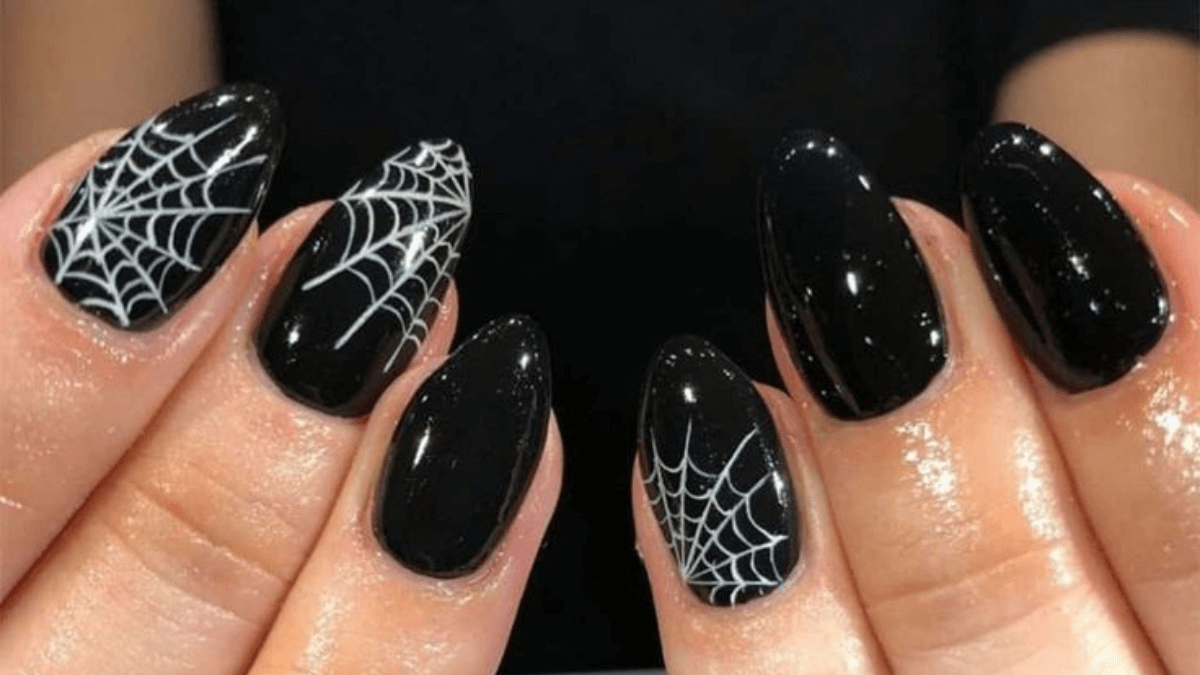 Uñas negras con detalles de telarañas en blanco.