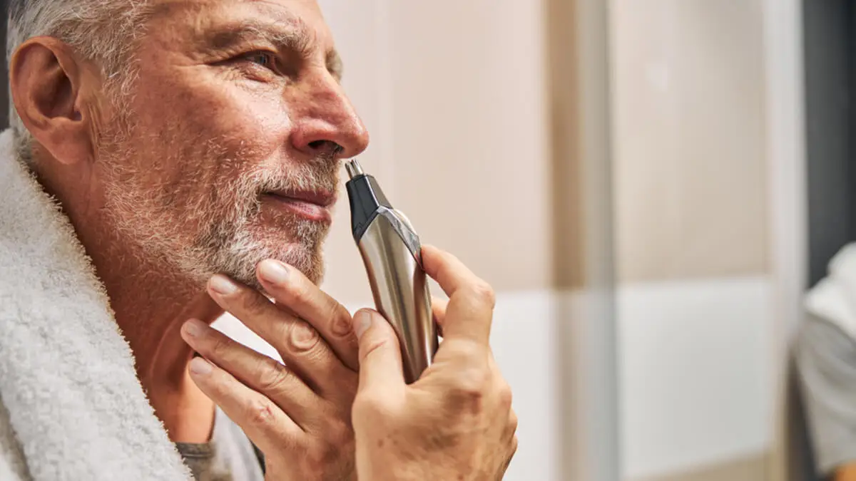 Hombre con recortador eléctrico para la nariz en la mano.