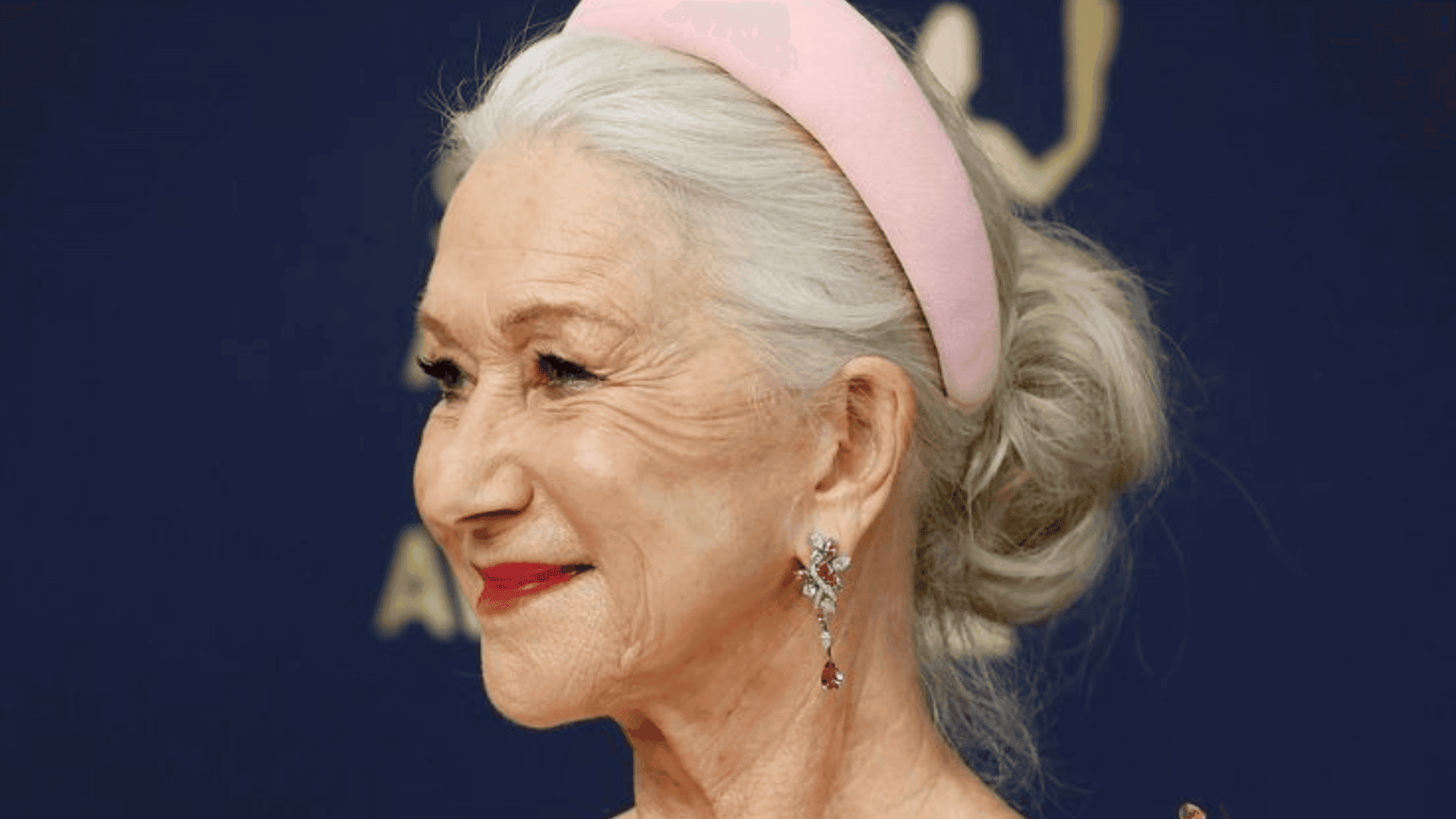 Mujer mayor luce diadema rosada con el cabello recogido.