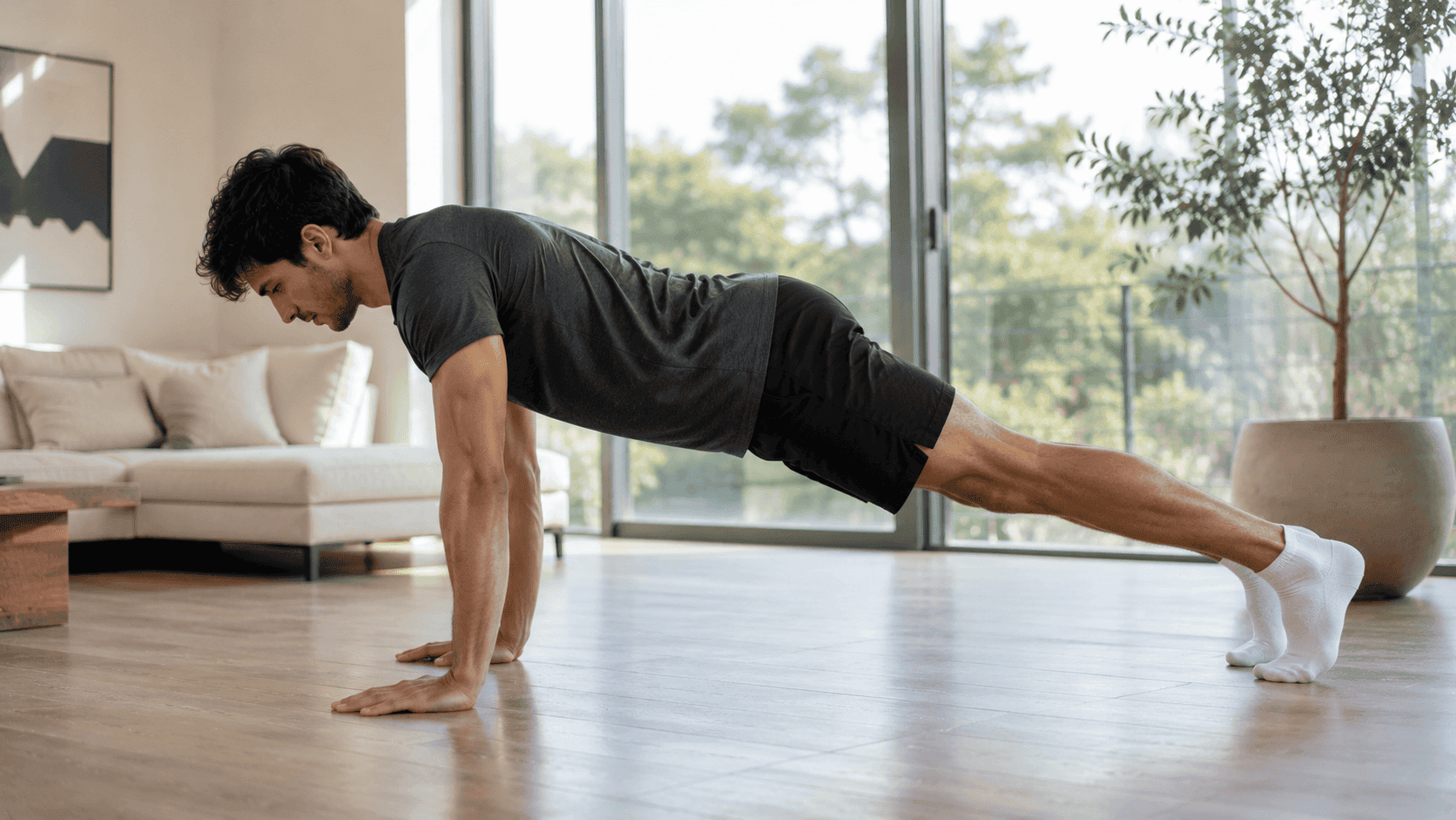 Hombre realizando una plancha con calcetines sobre una superficie lisa para fortalecer el abdomen y el core en casa.